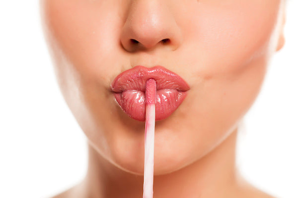 Close up of a woman applying hydrating lip balm to puckered lips, for our blog post on revitalizing lips.