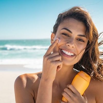 A woman applying sunscreen to her cheek