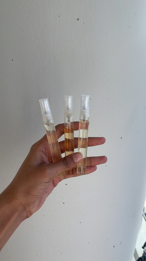 Someone holding 3 sample perfumes from Loomen abs