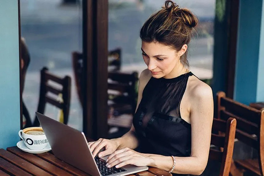 woman typing on laptop while sitting in a cafe