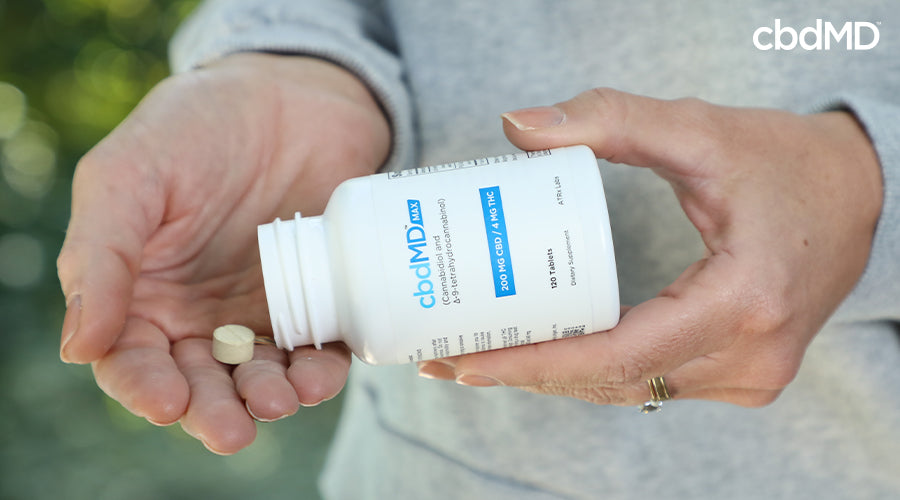 A woman holding and pouring max for pain 200 mg cbd 4 mg thc into her hand - cbdMD