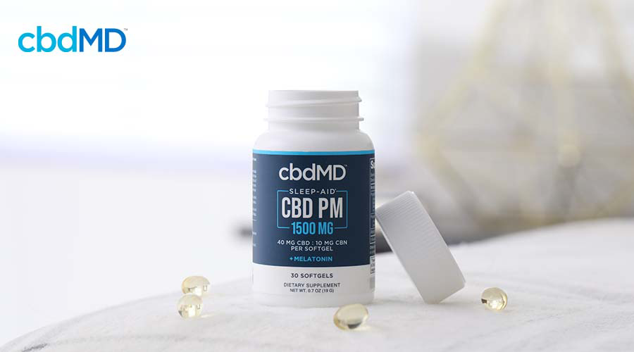 cbdMD sleep softgels with softgels next to them sitting on bed