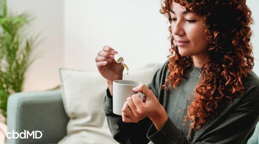 Woman Adding CBD Oil Tincture to Tea to Help with Natural Pain Relief