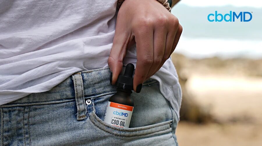 A woman slips a bottle of cbd oil tincture from cbdmd into her pocket