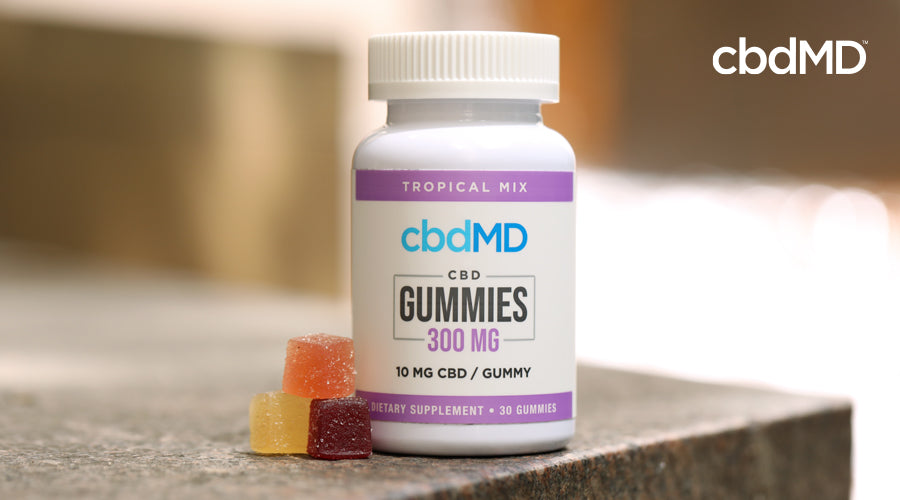 A bottle of 300 mg CBD gummies sits on a stone countertop