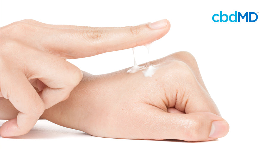 A woman's hands are shown applying a CBD topical cream