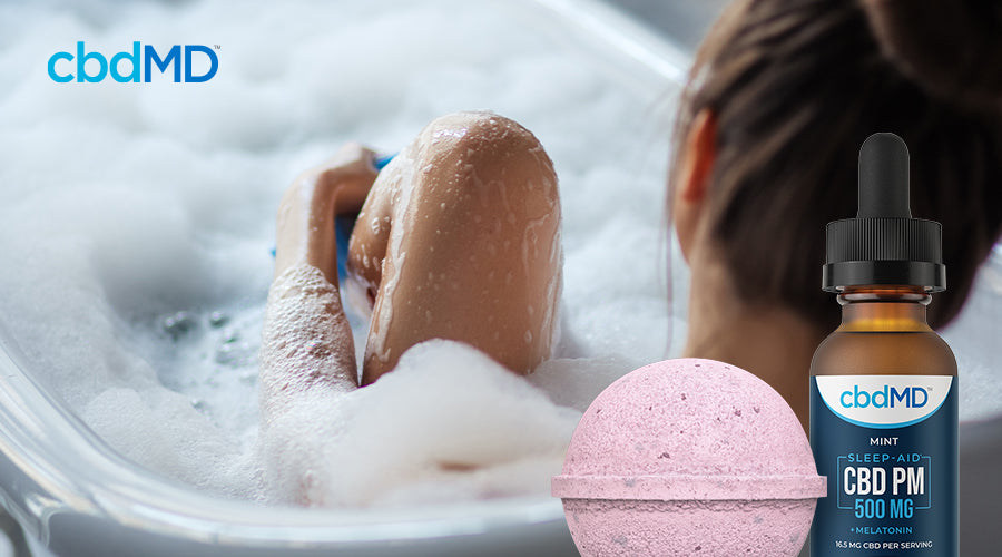 A woman relaxes in a bubble bath with a bottle of CBD PM and a pink bath bomb laid over the image in the foreground