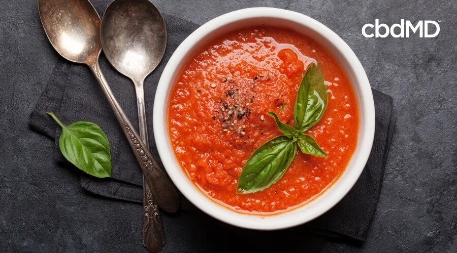 Un plato fresco de sopa de tomate se encuentra en un plato blanco encima de una mesa negra