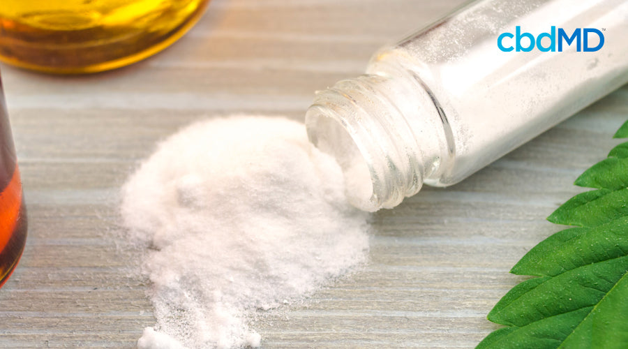 A white powder spills onto a table out of a slender glass jar