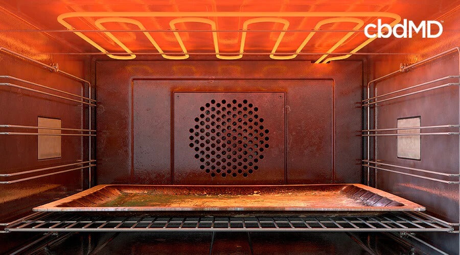 An aluminum baking pan sits inside a warm oven on the lower rack with red hot heating elements above it