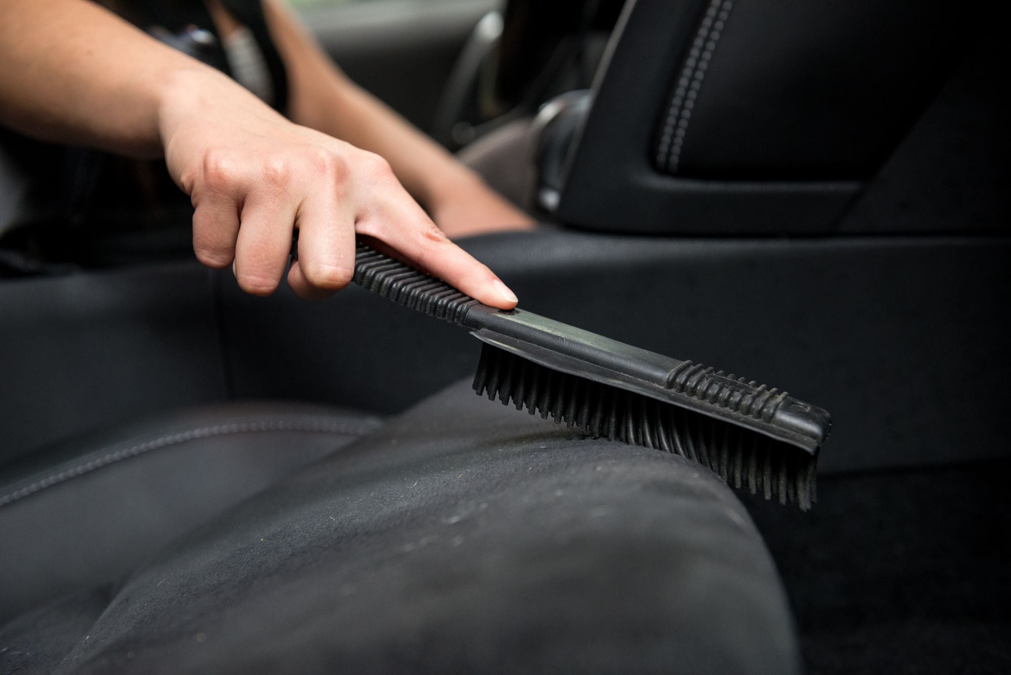 Removing pet hair from a black car seat with the Pet Hair Removal Brush