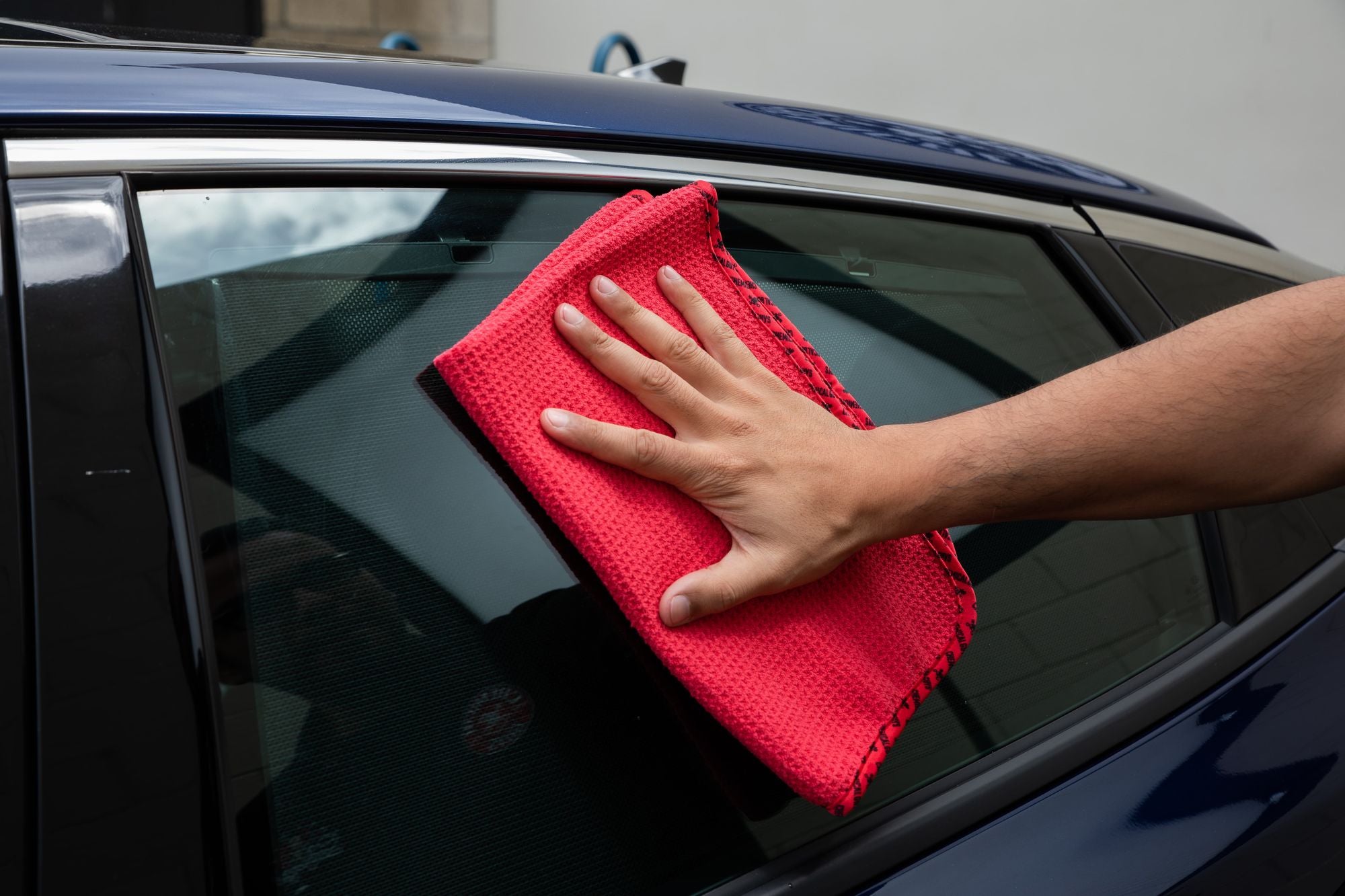 Red Waffle Weave Glass and Window Microfiber Towel wiping down a window.