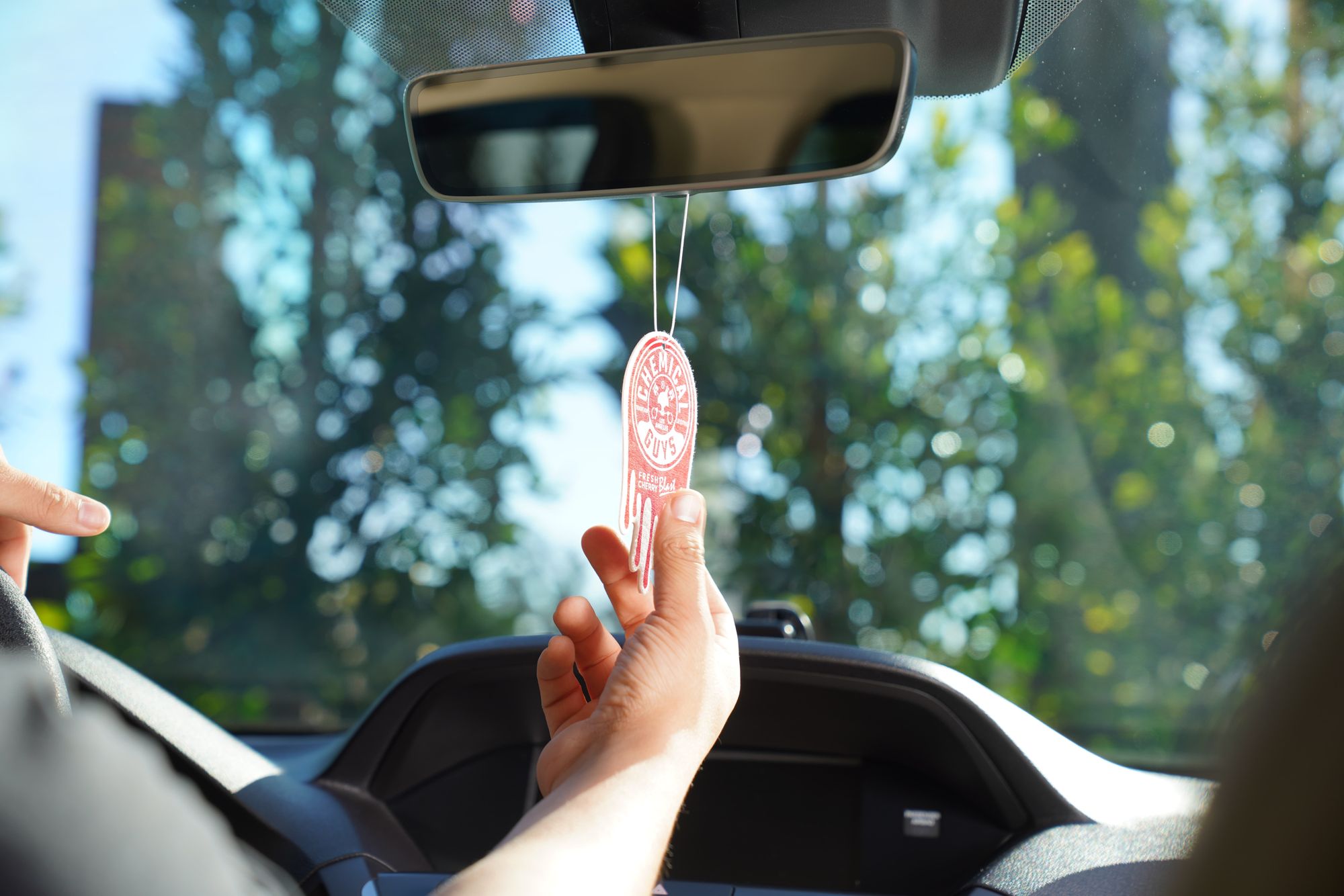 Hanging a Cherry Blast-scented Hanging Air Freshener on the rear view mirror