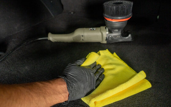 Wiping Car Mat with a Microfiber Towel with Da Machine Behind