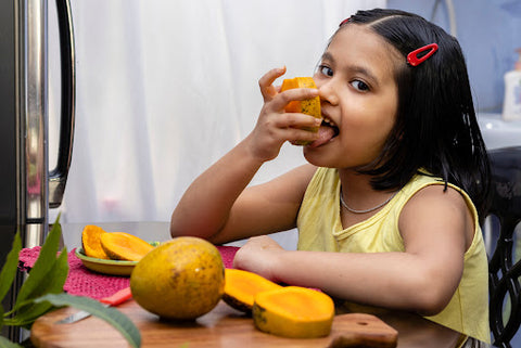 A girl eating fresh mangoes