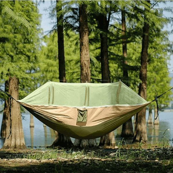 Portable camping hammock with mosquito net set up in the woods, featuring insect repellent