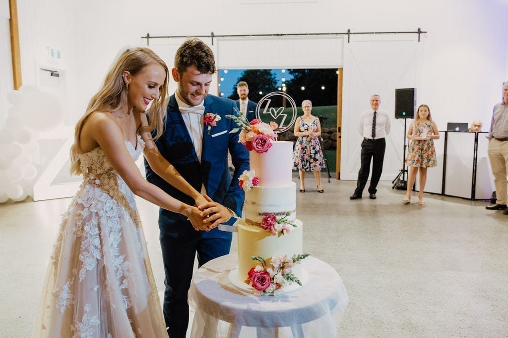 Newly weds cutting their cake by Milk and Honey Cake Creative