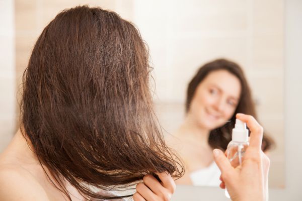 Woman Applying Heat Protecting Spray On Her Hair | ISA Professional