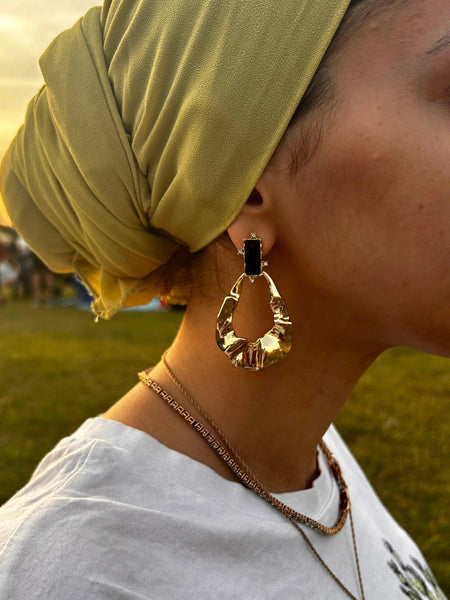 Close up on ear with maya Aztec gold and black tear rain drop shape dangle dangling drop fashion jewelry earrings - Roulette Safari