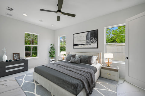 A virtually staged primary bedroom in a new construction home. It is staged with modern white furniture and decor.