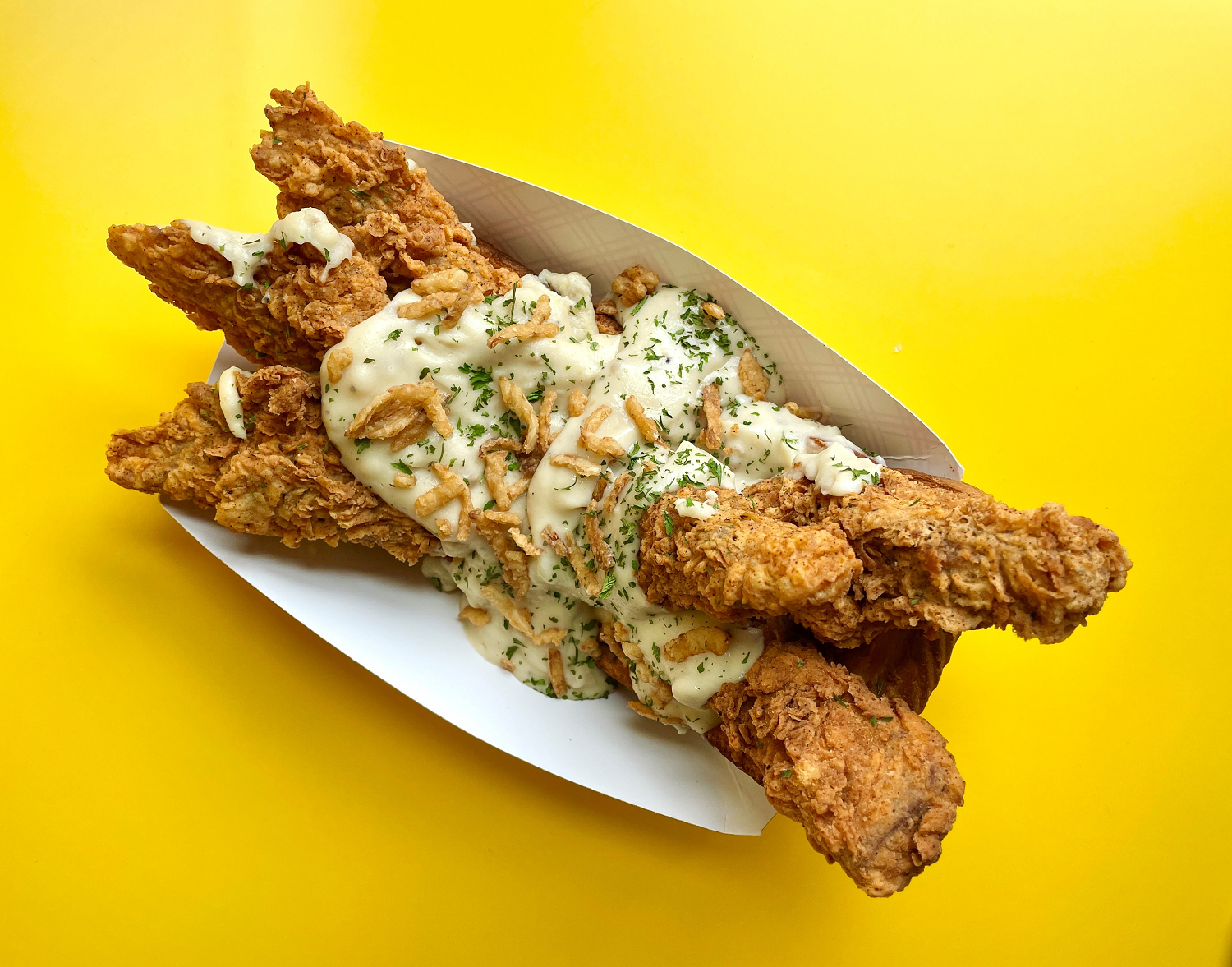 paper boat with texas toast, six fried chicken and chicken-fried steak tenders, topped with white gravy, fried onions and parsley flakes for the minnesota state fair 