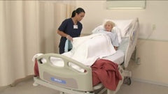Nurse attending to elderly patient in hospital bed