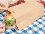 Sandwich being placed inside Duro Bag brown paper bag