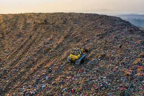 Bulldozer plowing landfill up hill