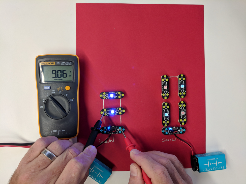 Circuit Scribe ink and modules showing a parallel circuit next to a series circuit with a multimeter measuring voltage of the parallel circuit as 9 volts