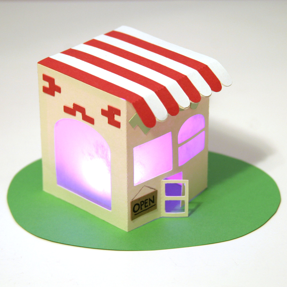 Paper craft house with windows that glow pink from a color blender circuit inside