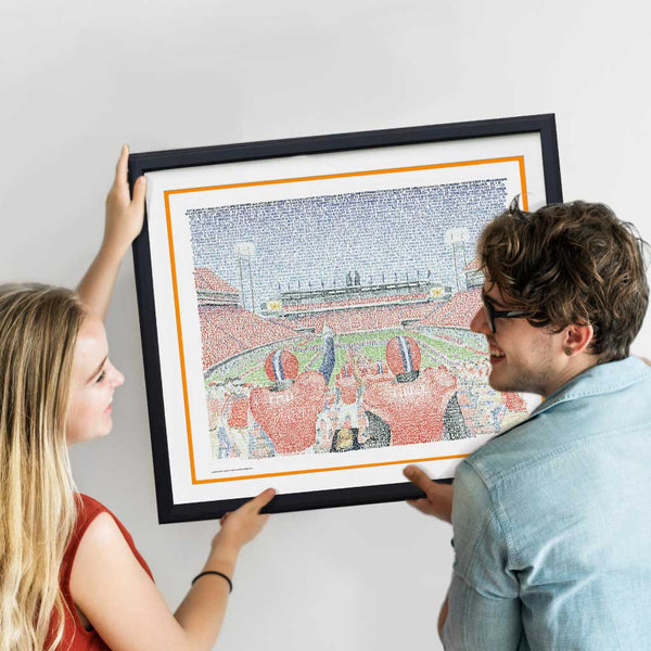 Woman and man smile while hanging framed word art of Clemson’s Memorial Stadium, handwritten with Tiger wins through 2019.