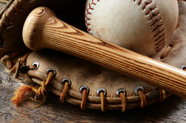 Tip and handle of wooden baseball bat and old baseball rest in a leather baseball glove. 