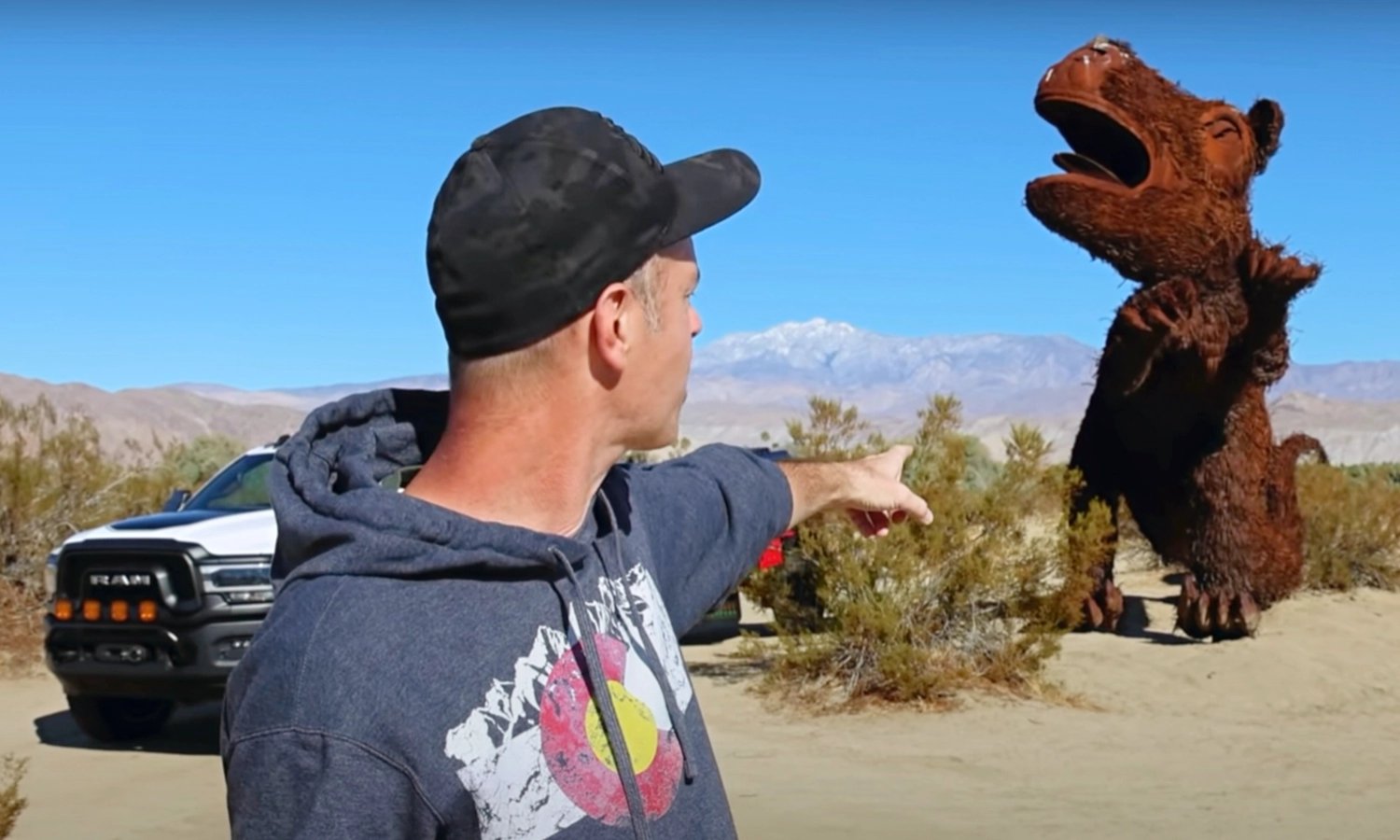 Brad from TrailRecon points at a giant, metal sculpture of a giant sloth in Galleta Meadows near Anza-Borrego State Park.