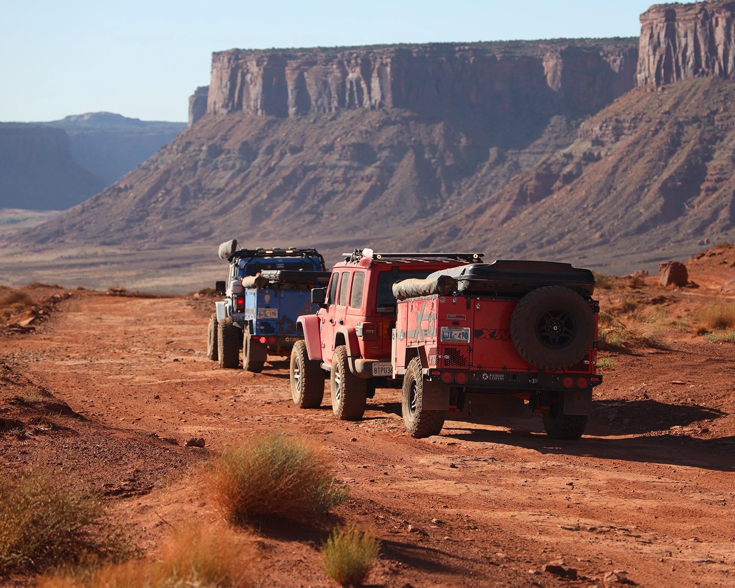 Red and blue jeeps driving off-road in the desert