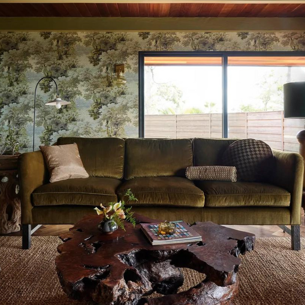 Ranch style home with Western-style wallpaper, dark couch, and wood coffee table