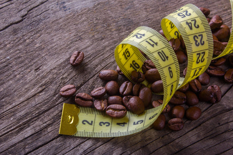 An image of coffee beans surrounded by a tape measure on a wood grain background.