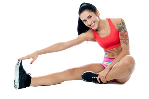 An image of a fit, athletic woman doing stretching exercises on the floor.