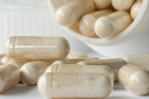 An image of postbiotic supplement capsules spilled out of the pill bottle. 