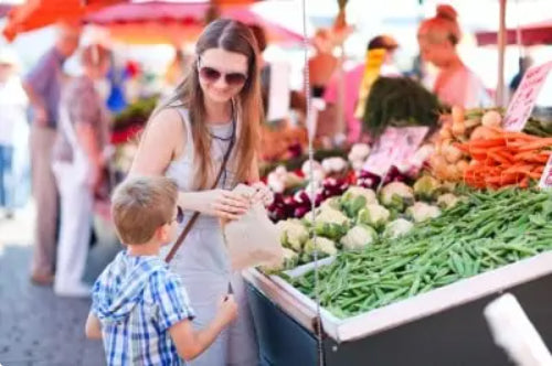 Mom and son getting vegetables at farmers market.