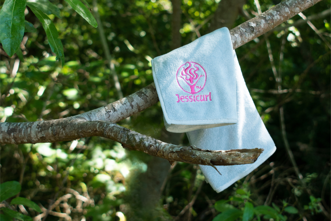 Jessicurl branded towel hanging on a tree branch in the forest