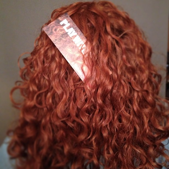 back of red, curly haired woman's head with a bookmark in her hair