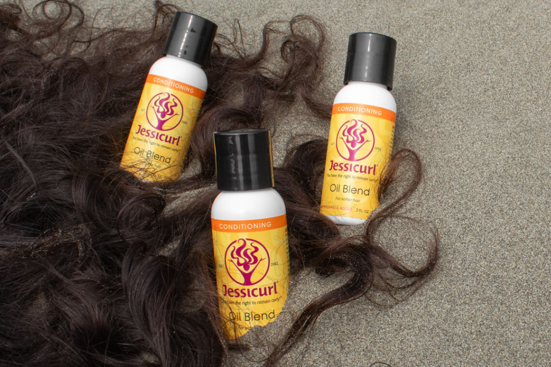 brown curly hair on a sandy beach surrounding three bottles of product