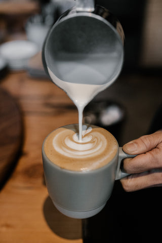 pour steamed milk into a cup to make a latte