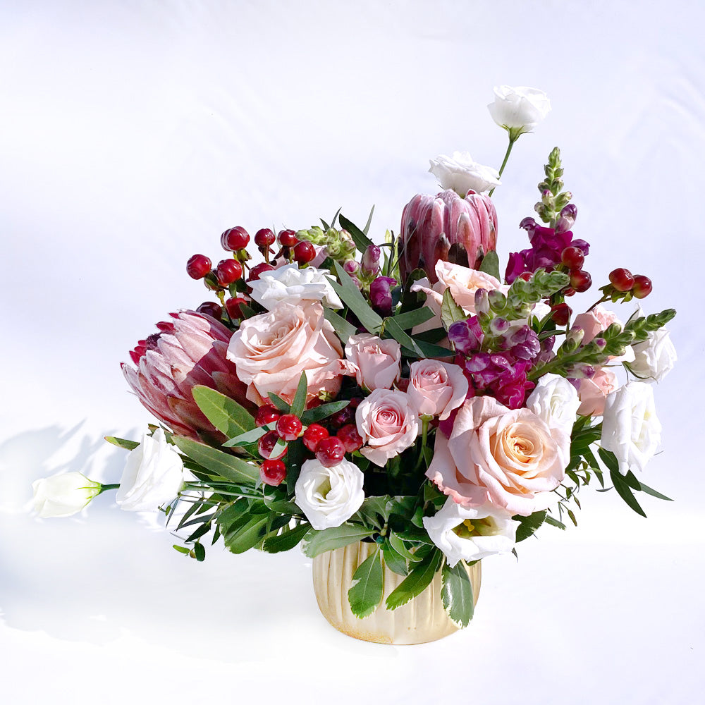 You Make Me Blush with protea, lisianthus, snapdragon. Features blush, red and white and a gold vase