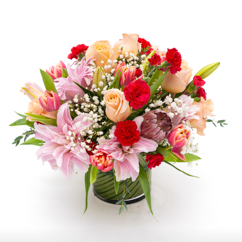 Double lily, double tulip, minicarnations in tones of reds, peaches, pinks with rich greens.