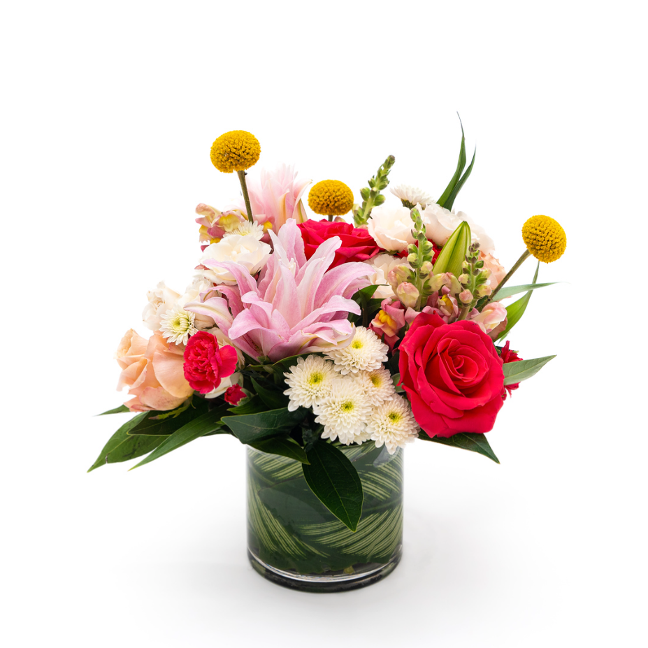 White buttons sit next to bright pink and peach roses, double lilys, hot pink mini carnations are complemented by yellow billy balls and pink snapdragon