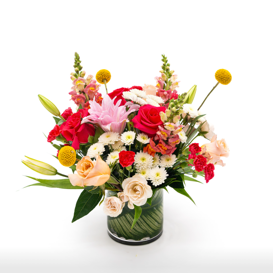 White buttons sit next to bright pink and peach roses, double lilys, hot pink mini carnations are complemented by yellow billy balls and pink snapdragon