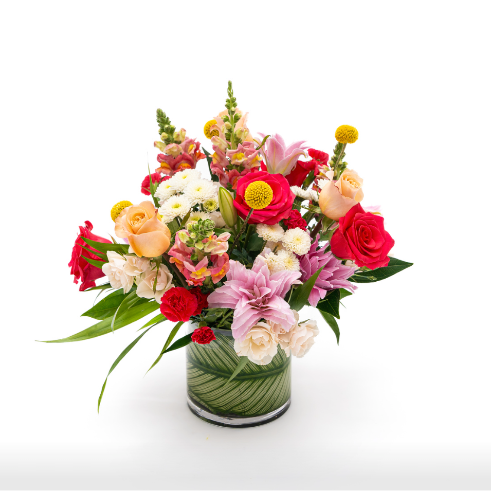 White buttons sit next to bright pink and peach roses, double lilys, hot pink mini carnations are complemented by yellow billy balls and pink snapdragon