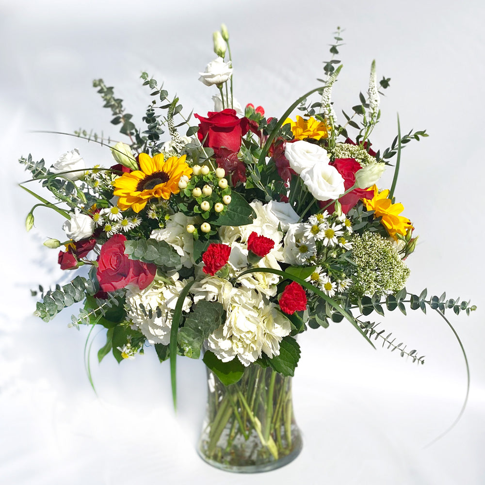 Sunflowers, Red roses, White Lisianthus, with Eucalyptus and pops of white flowers and sultry textures.