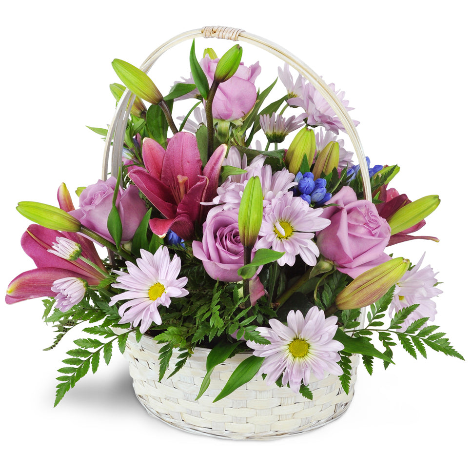 Basket Full of Dreams. An assortment of purple-hued roses, daisies, lilies, and more are arranged in a white, handled basket.